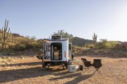 airstream rei co op basecamp trailer shown from the back with desert in the background and campsite set up around it