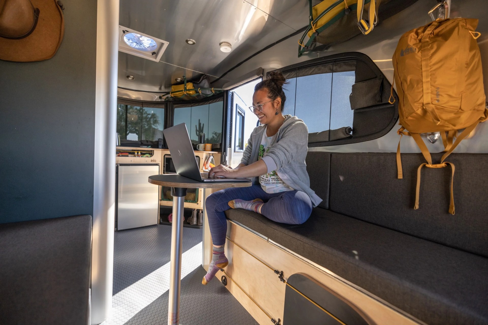 interior of airstream rei camping trailer with woman working on a laptop at a table