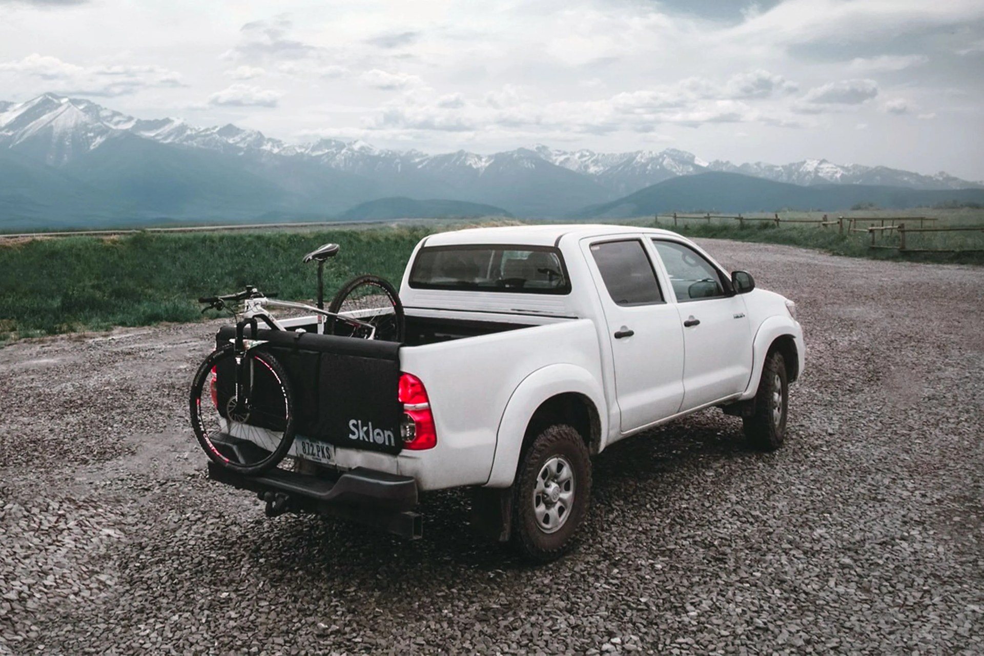 white truck parked on gravel overlooking mountains with a sklon bike mat and bike in back of truck bed