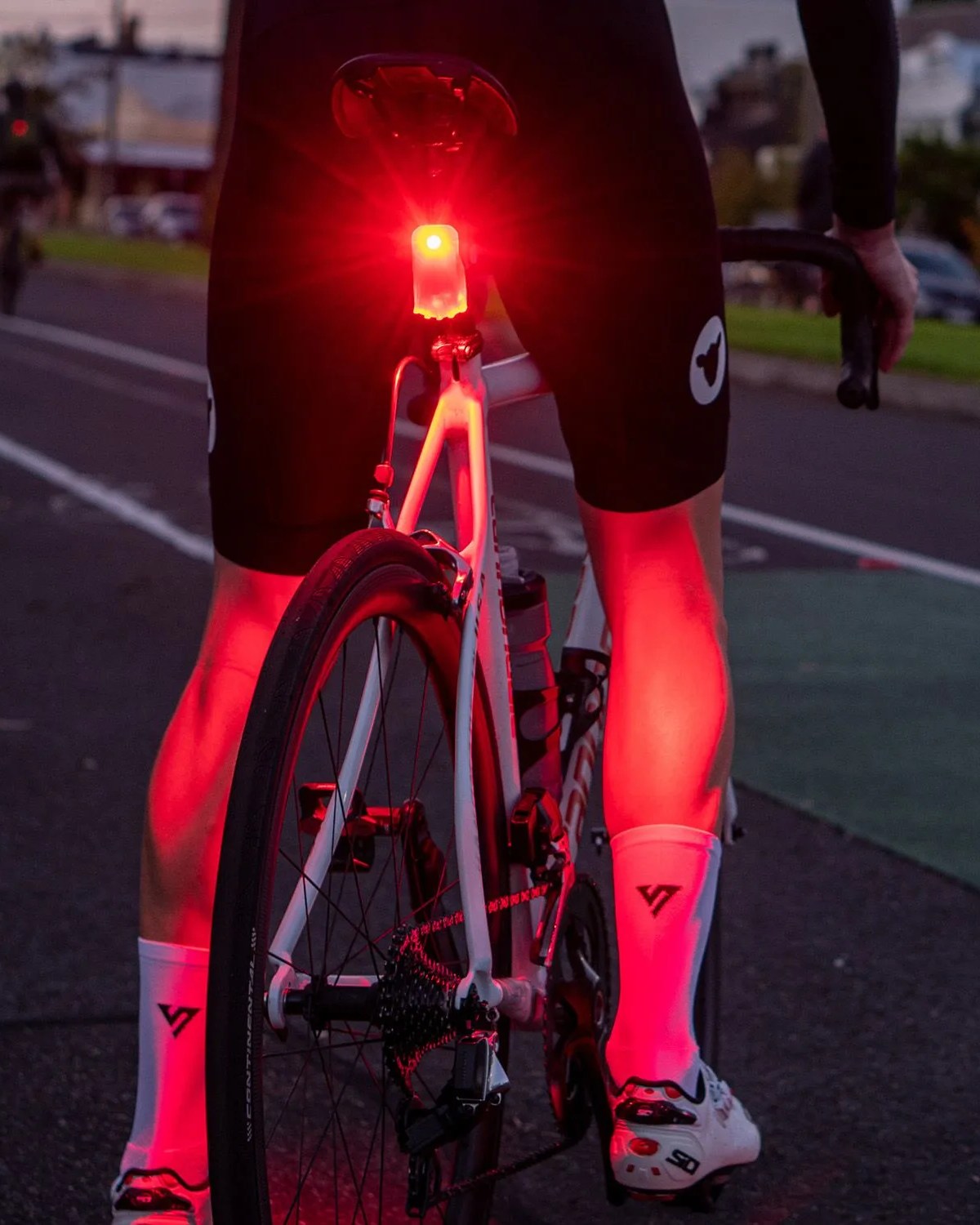 person sitting on bike at night with red project flock light