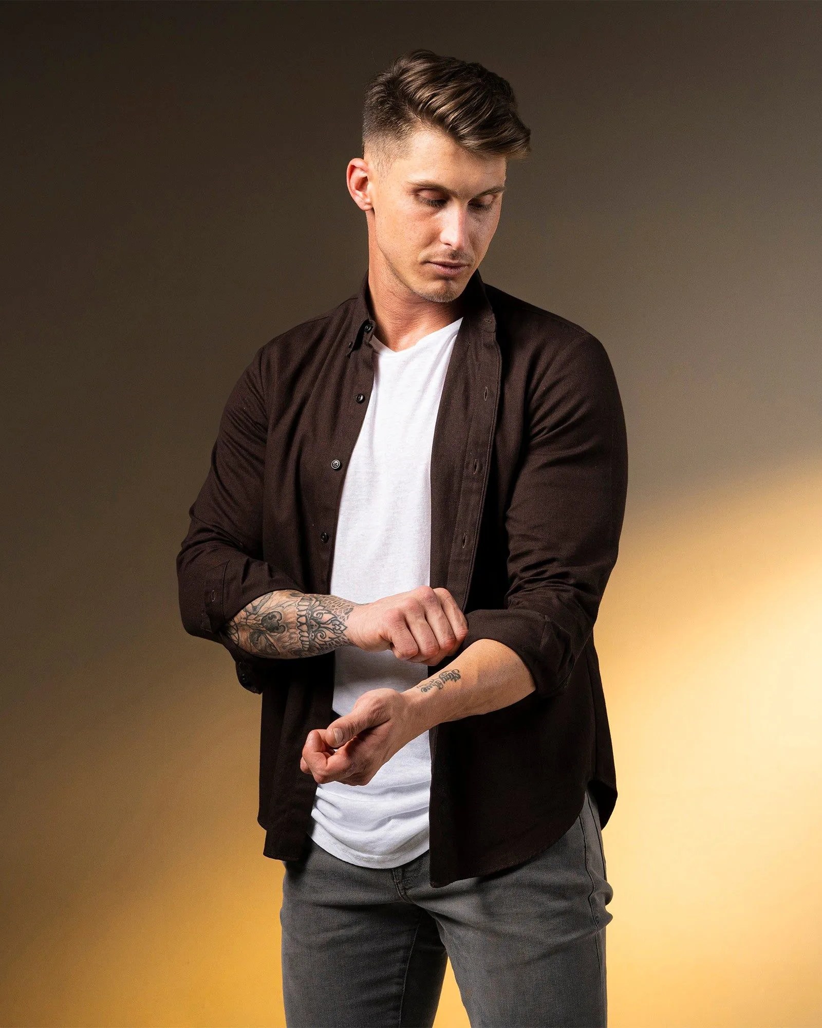 man adjusting the sleeves on the weekender button down in ganache