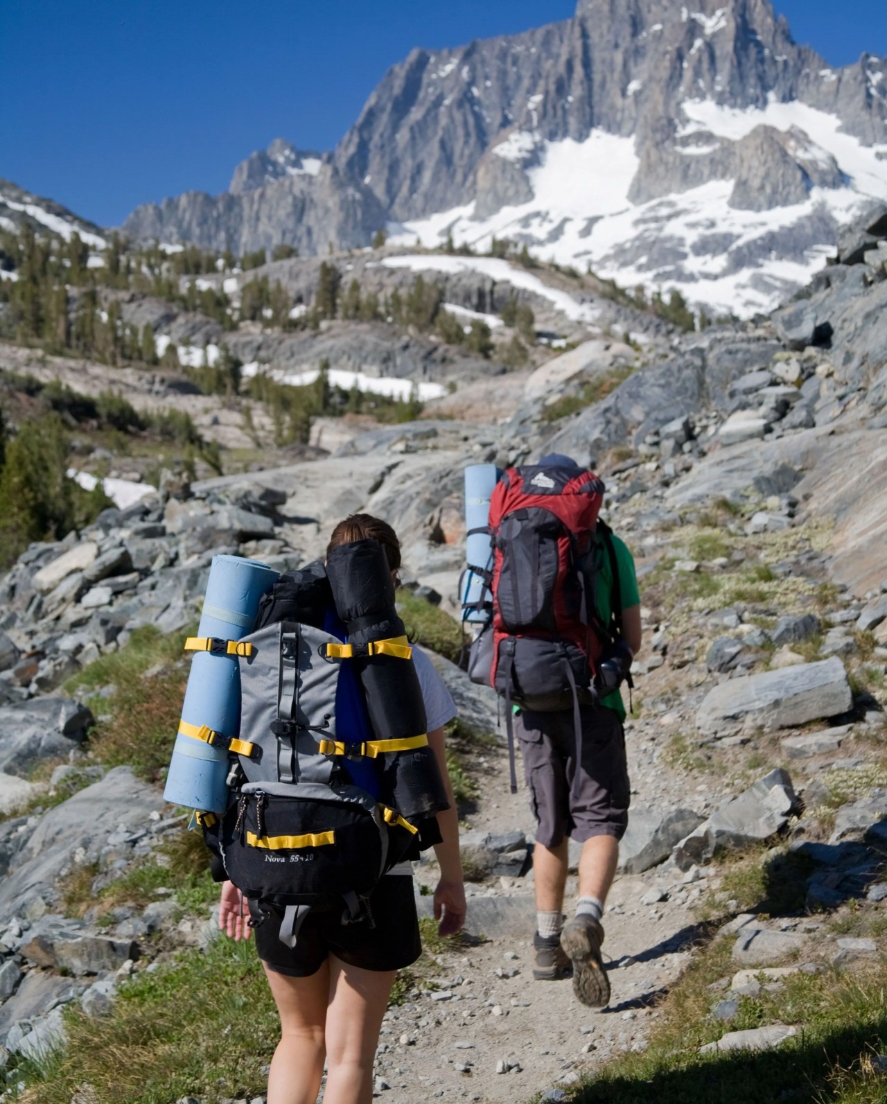 two people hiking up mountain terrain wearing out and back gear