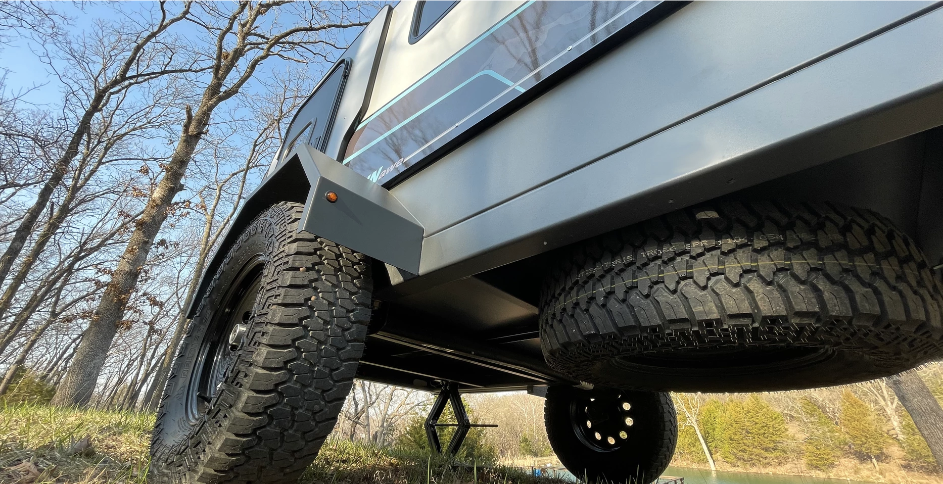 underneath campinawe camping trailer with all terrain tires and a spare