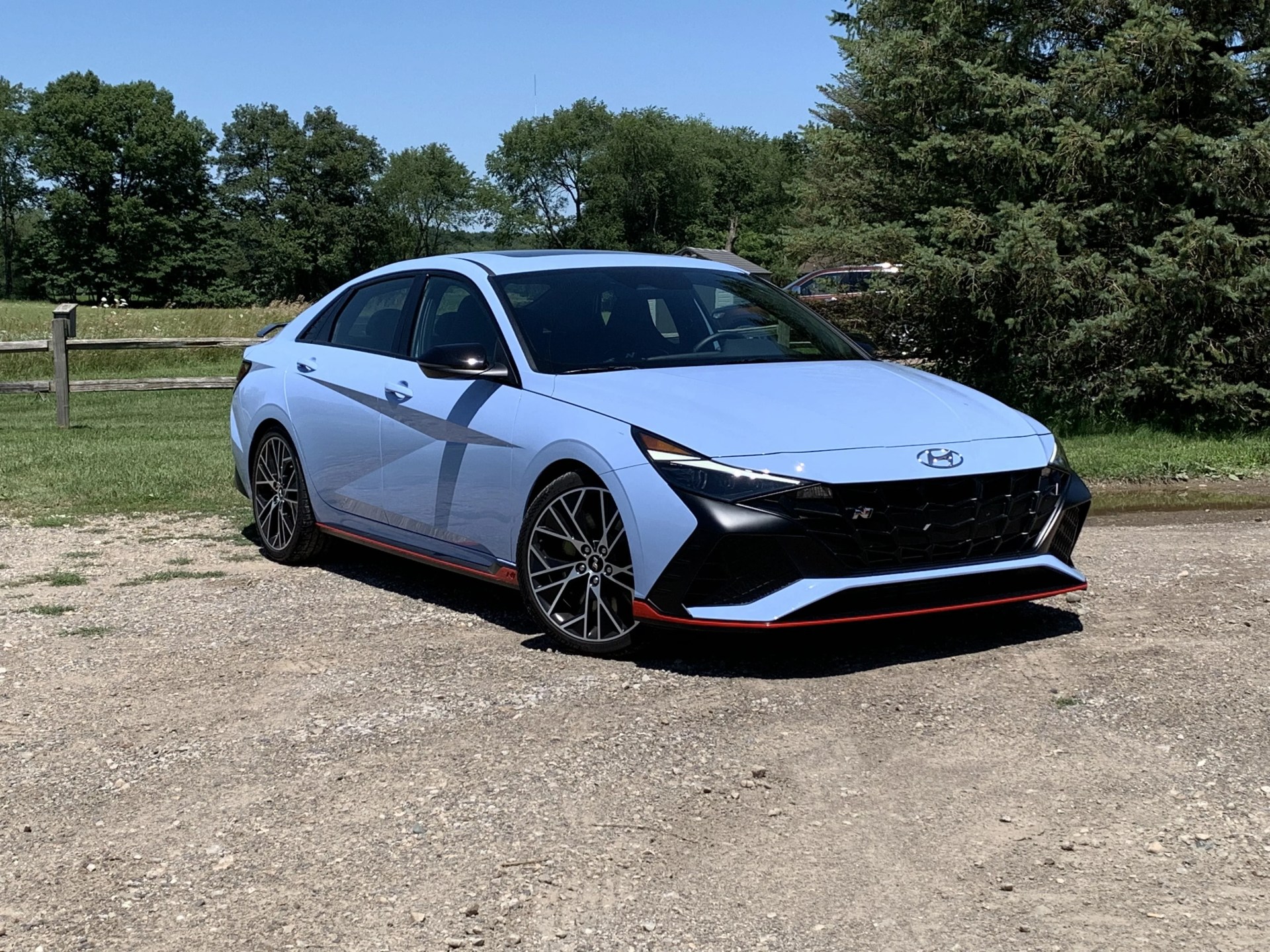 hyundai elantra n parked in a dirt lot with a field in the background