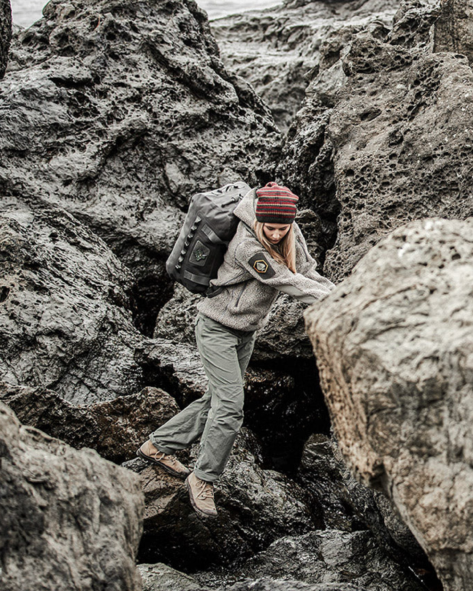 a woman scaling rocks while carrying a  prometheus design werx all terrain duffel 60l