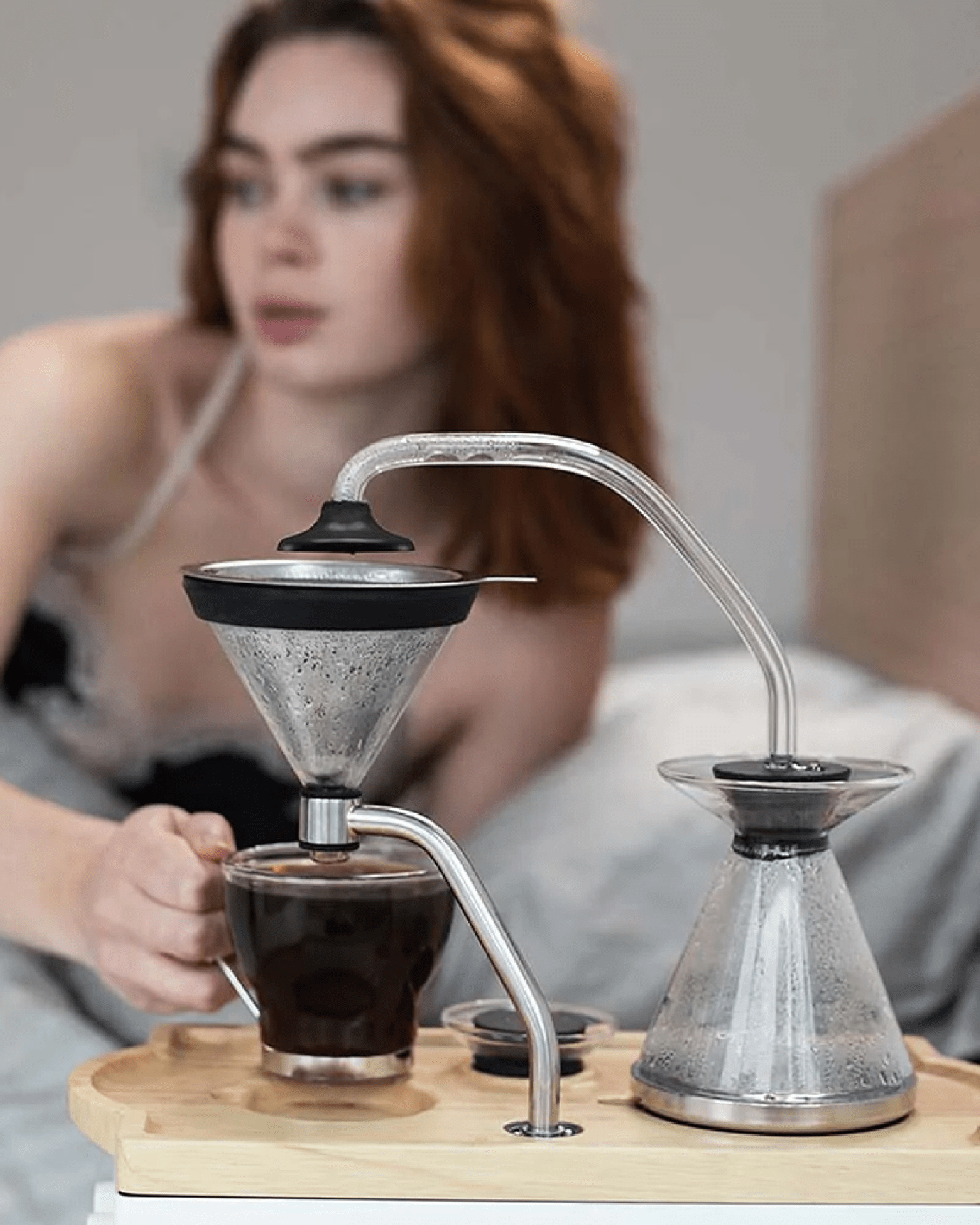 a woman grabbing a cup of coffee brewed by a joy resolve barisieur tea and coffee alarm clock