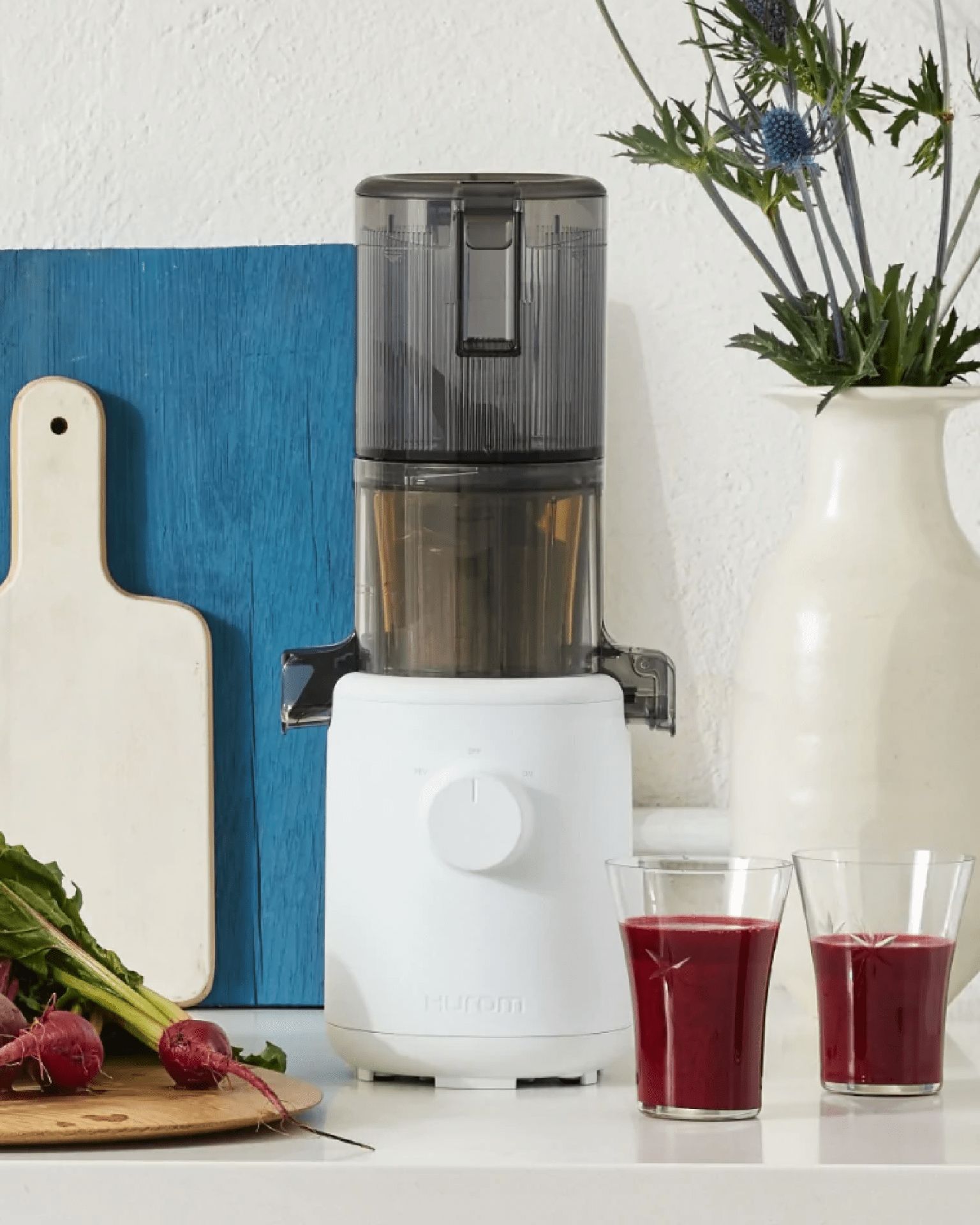 h310 easy clean slow juicer in a kitchen setting next to 2 glasses of red juice