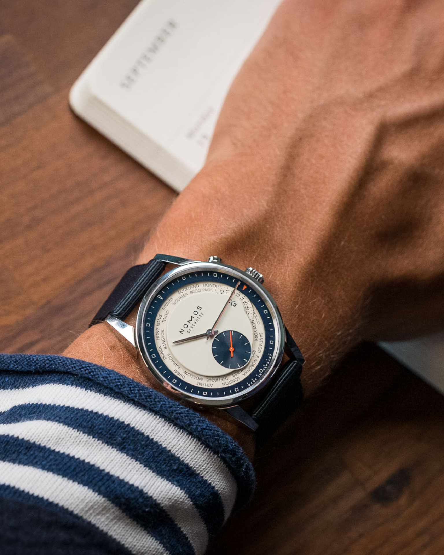 a man wearing a fratello x nomos glashütte collab watch with a blue and white dial