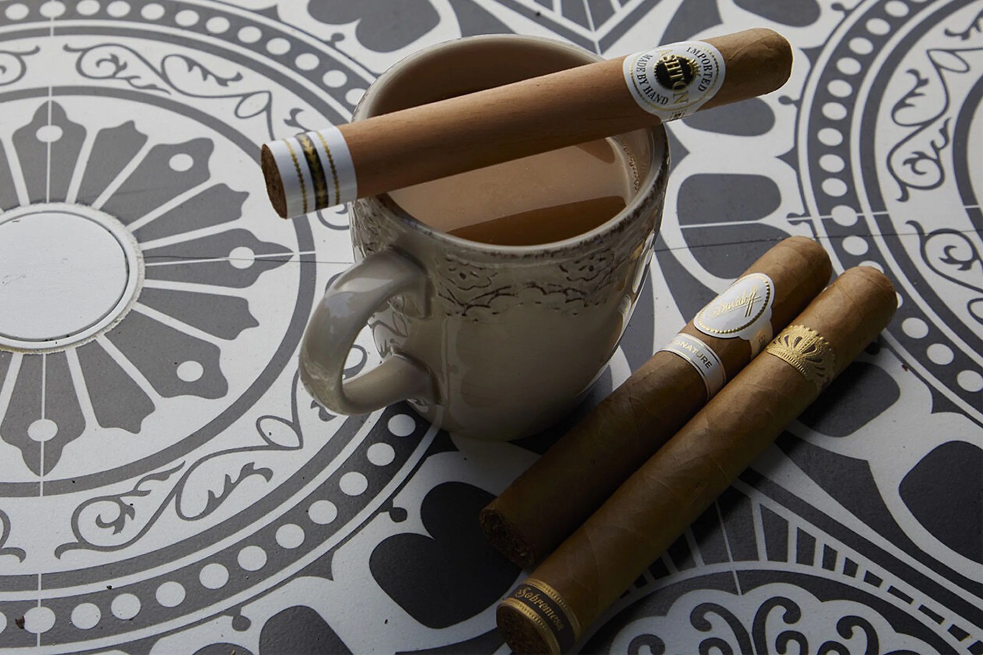 cigars on a table with a cup of coffee