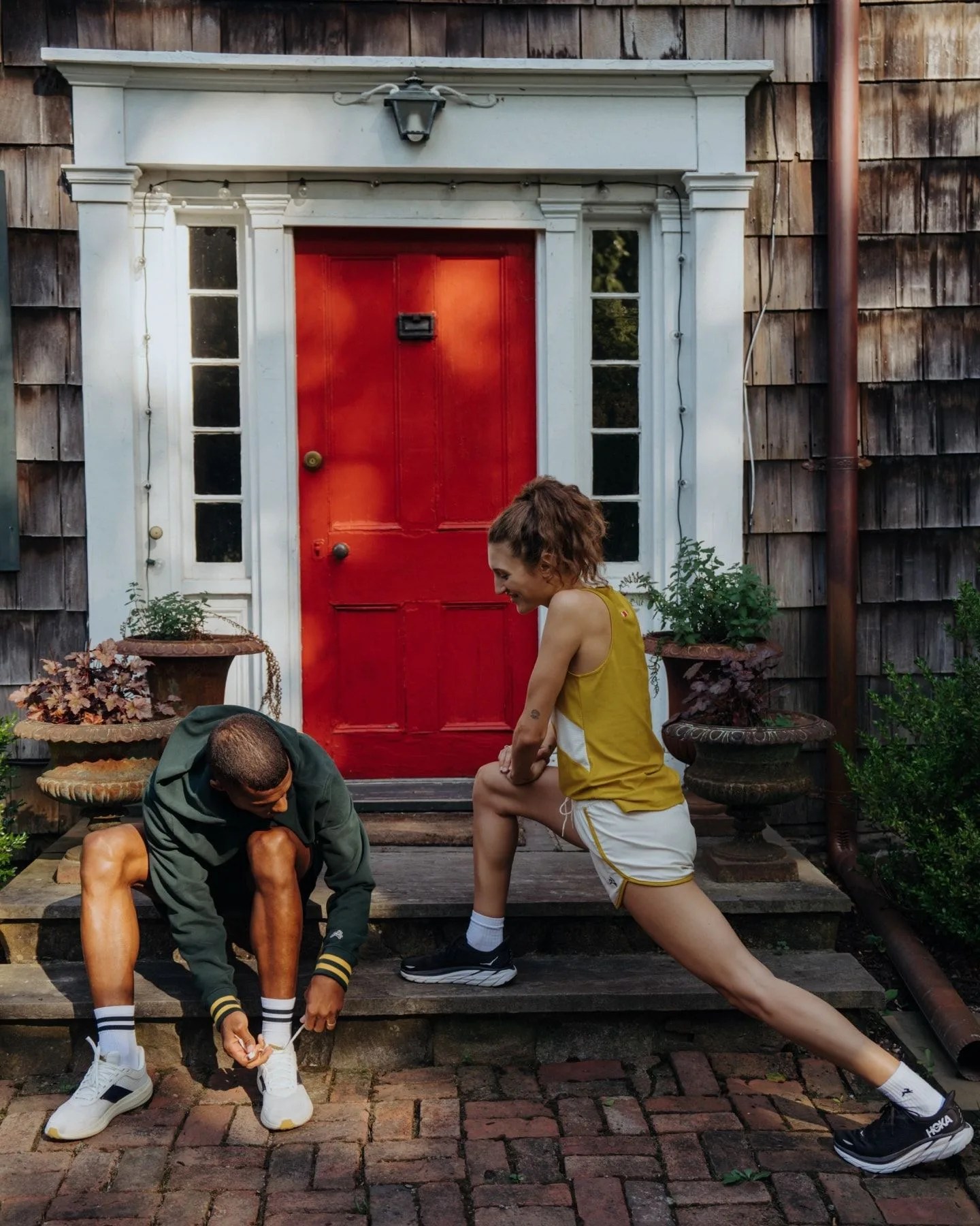 man and woman stretching to prepare for a run while wearing tracksmith gear