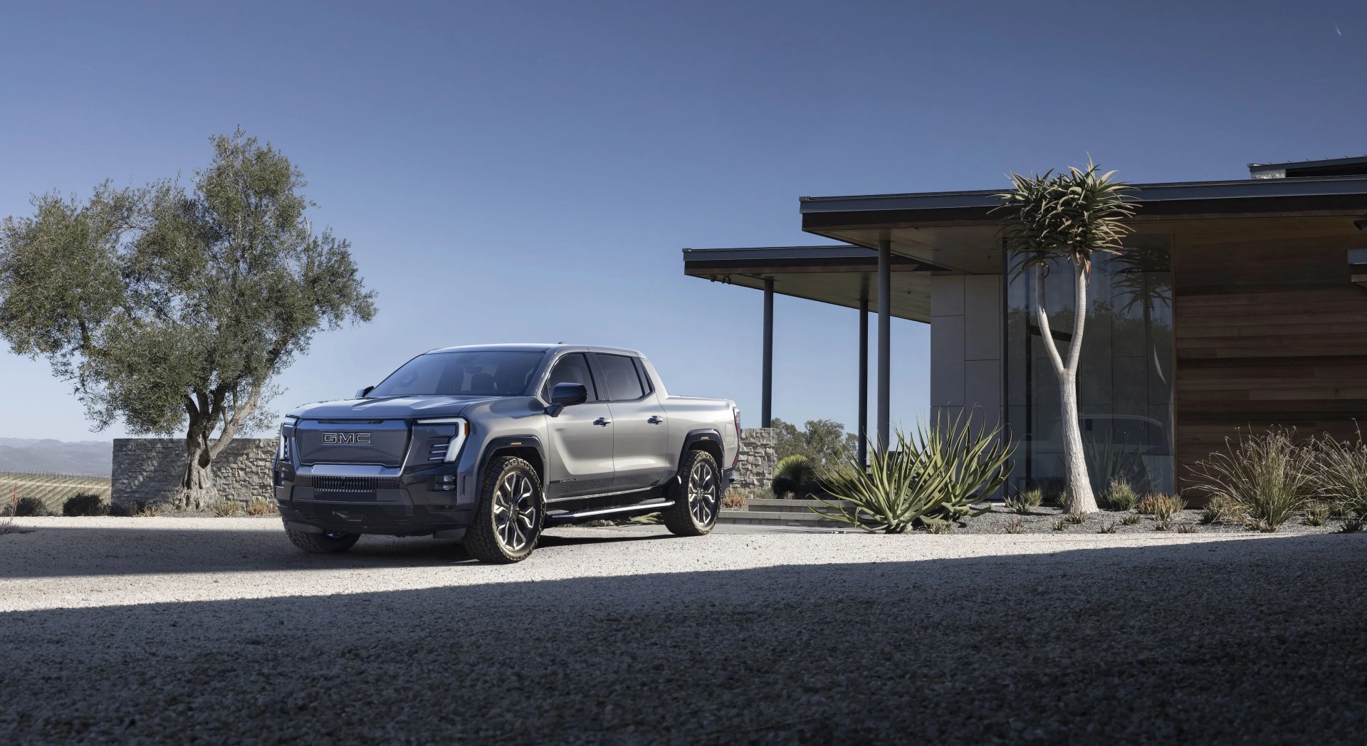 gmc sierra ev parked in front of a swanky house in the desert