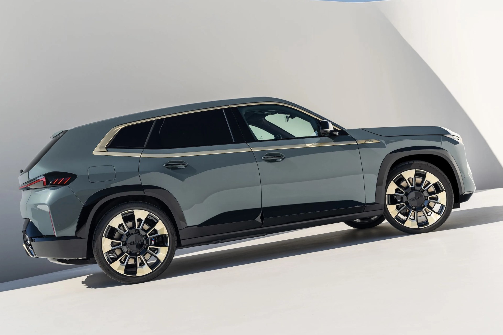 bmw xm parked on a hill in front of a white wall