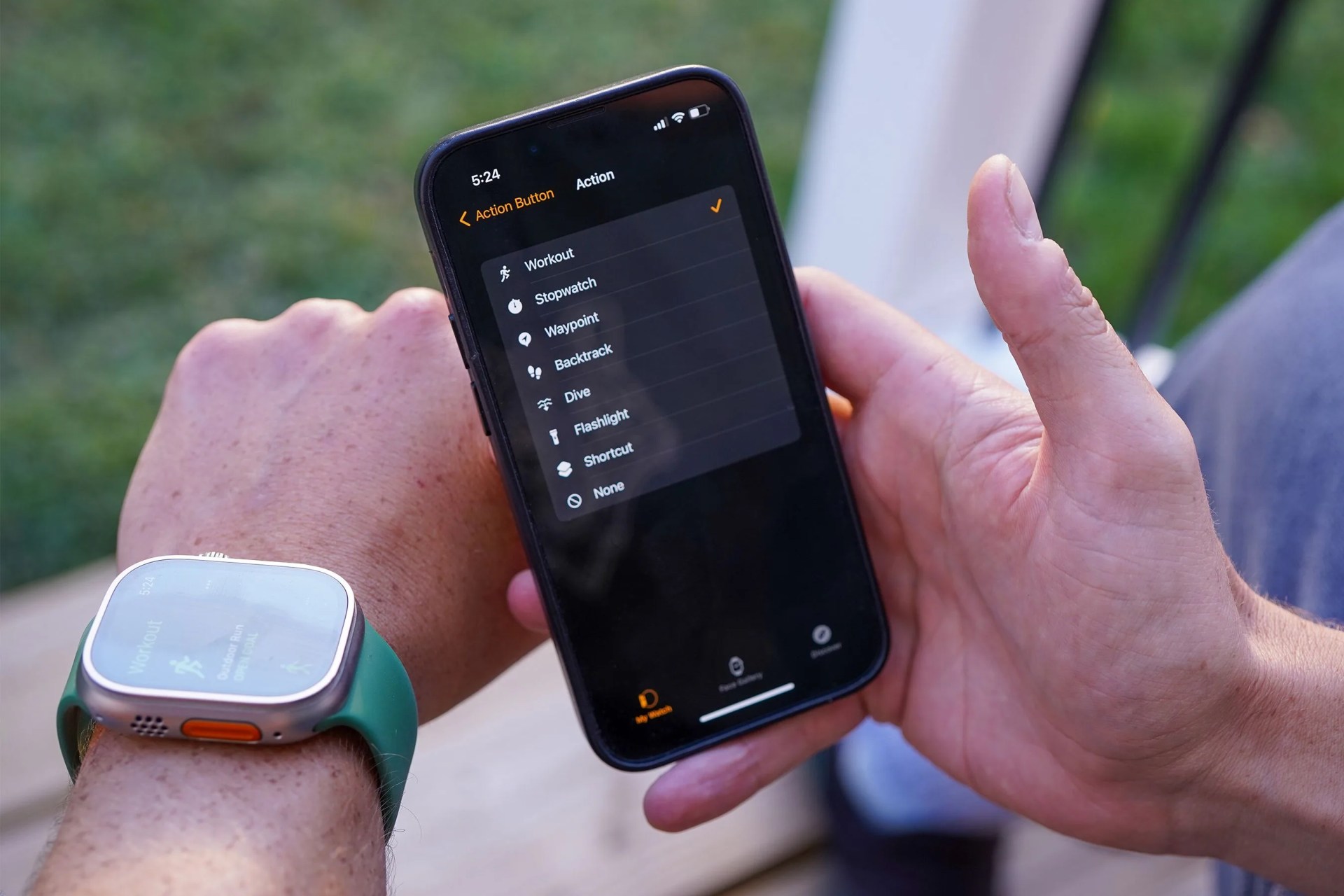 man wearing an apple watch ultra and looking at the settings screen on an iphone