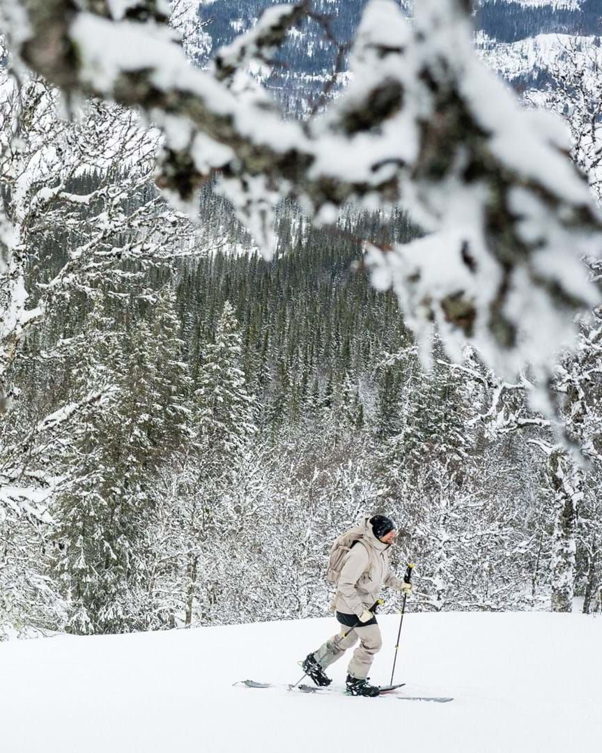 man walking in snow wearing skis in houdini sportswear