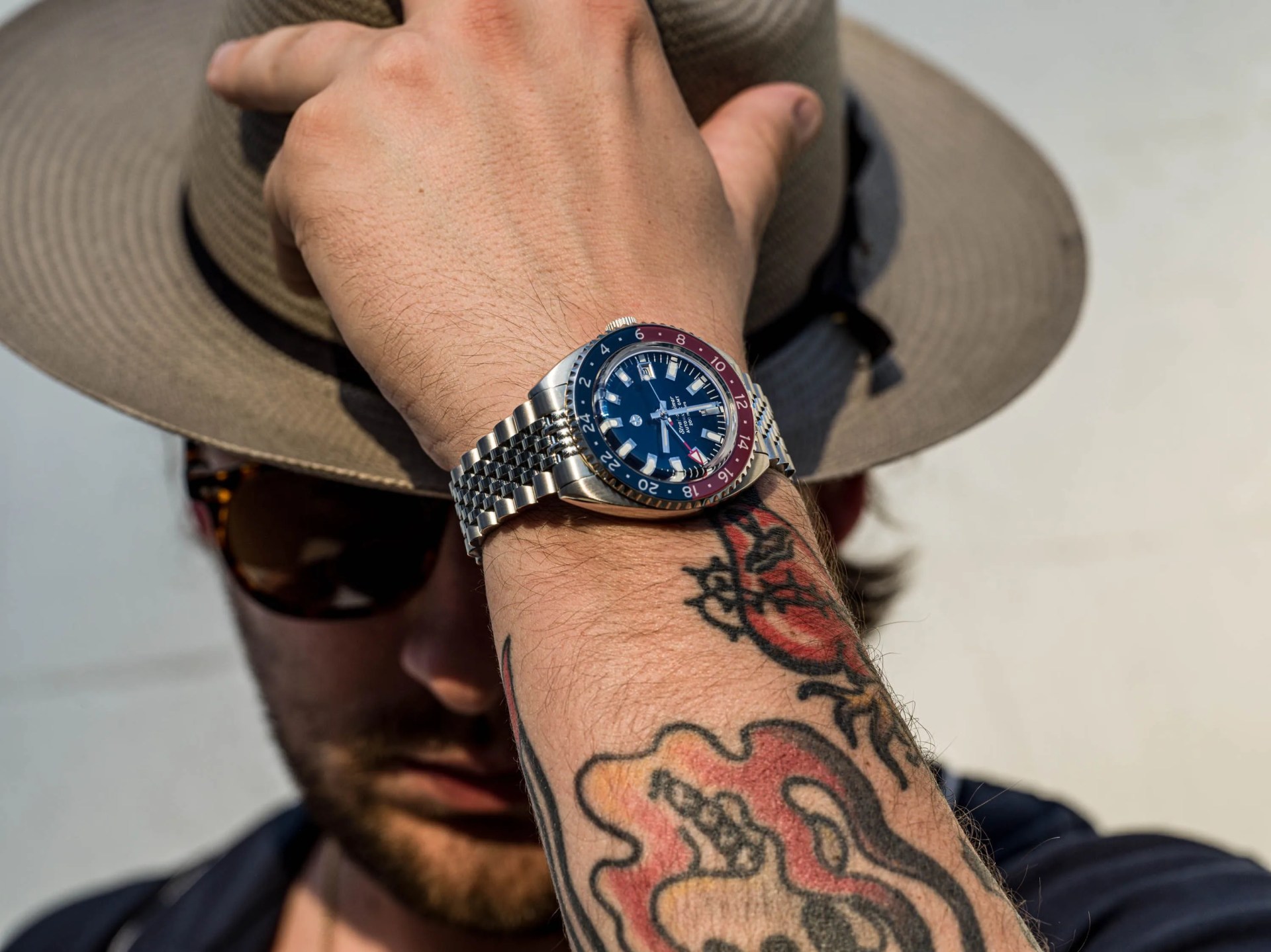 man taking off a hat while wearing a watch on his wrist