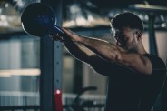 man building muscles with kettle bell