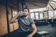 man drinking water after training in gym