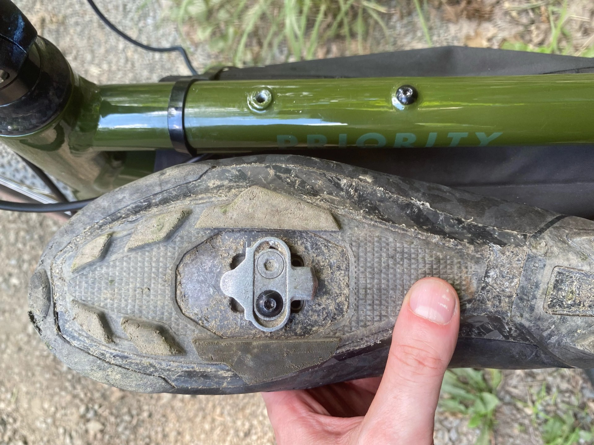 the underside of a bike shoe next to the middle bar of a priority apollo bike