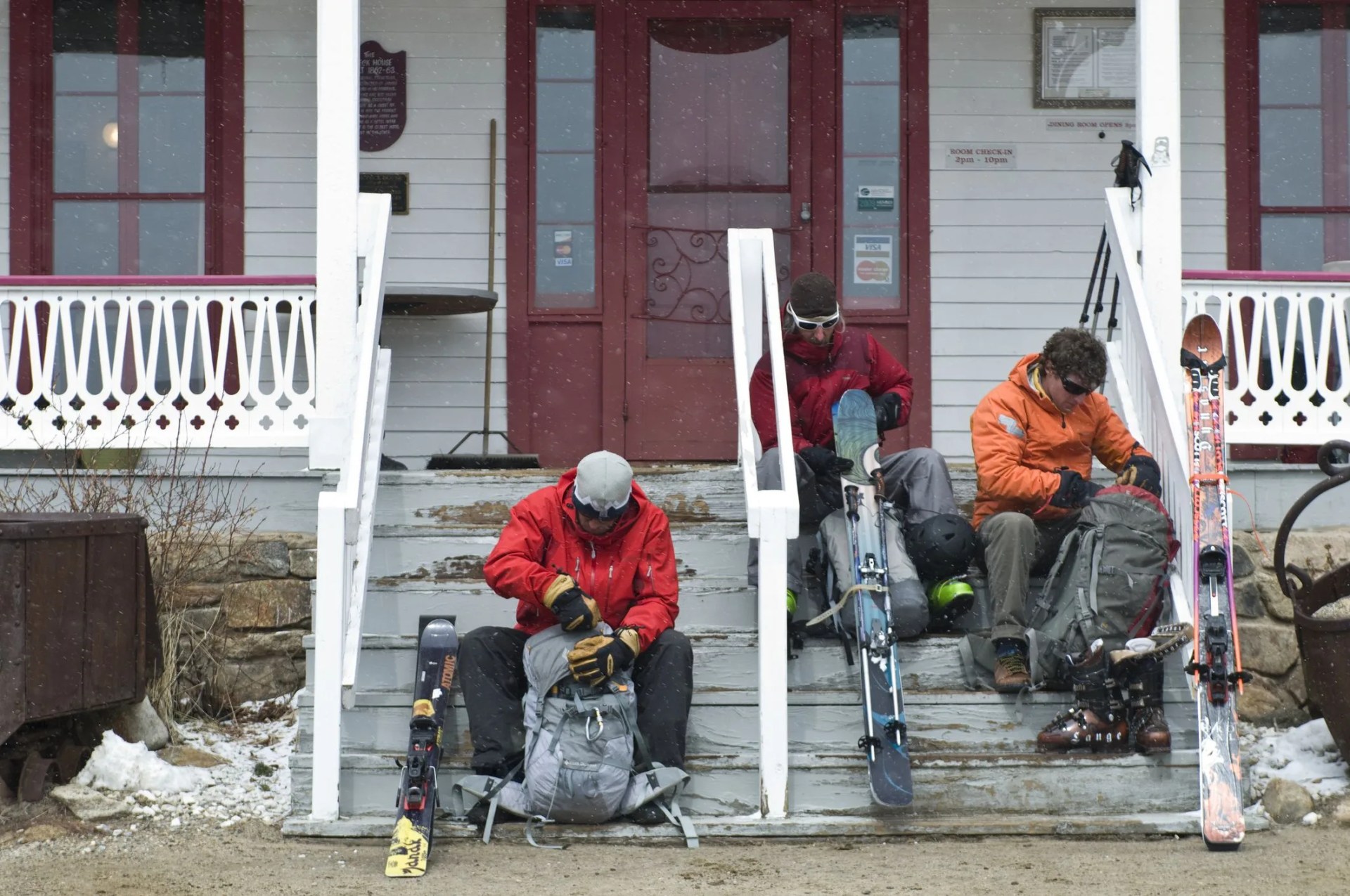 skiers going through packs on porch of old house