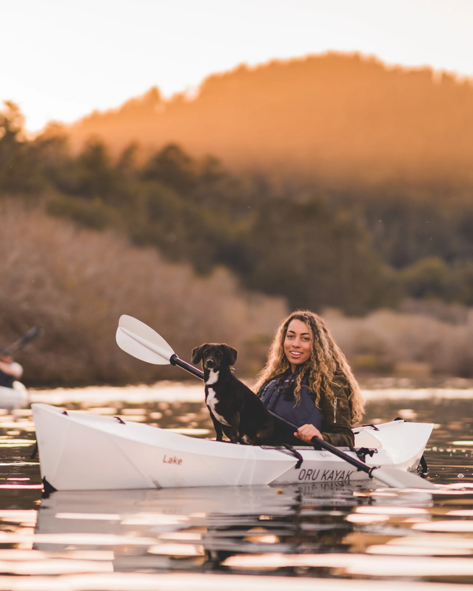 a person and dog in a oru kayak on the water