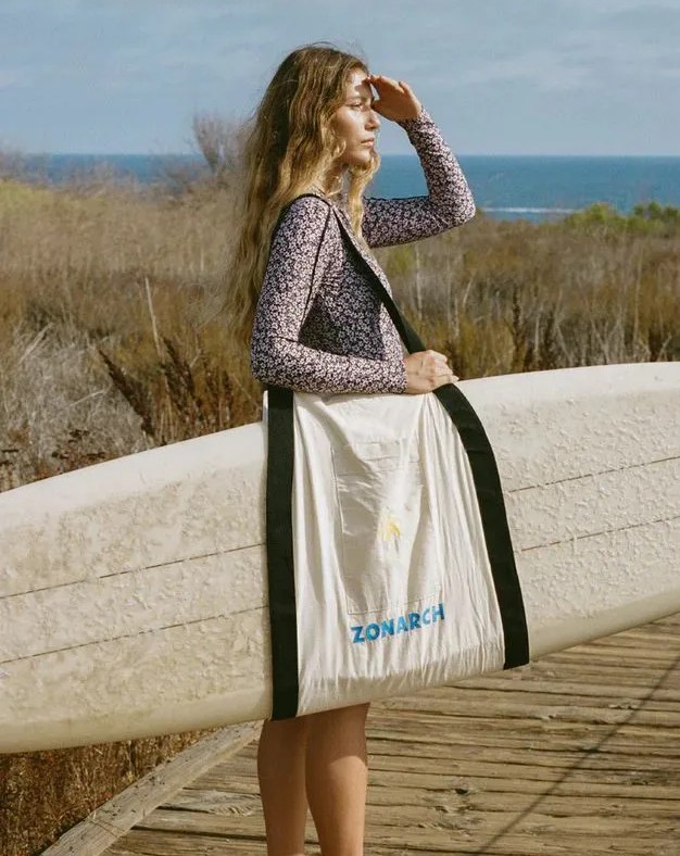 woman looking into the distance using zonarch le board bag to carry her surfboard