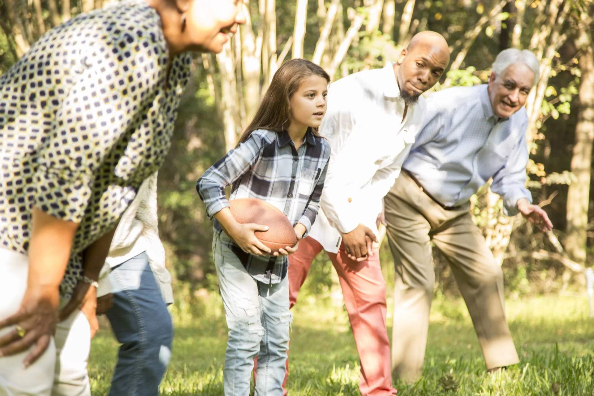 multi ethnic family playing football in backyard at thanksgiving