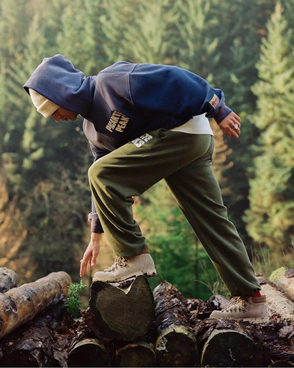 man hiking across logs wearing picante peak sweats