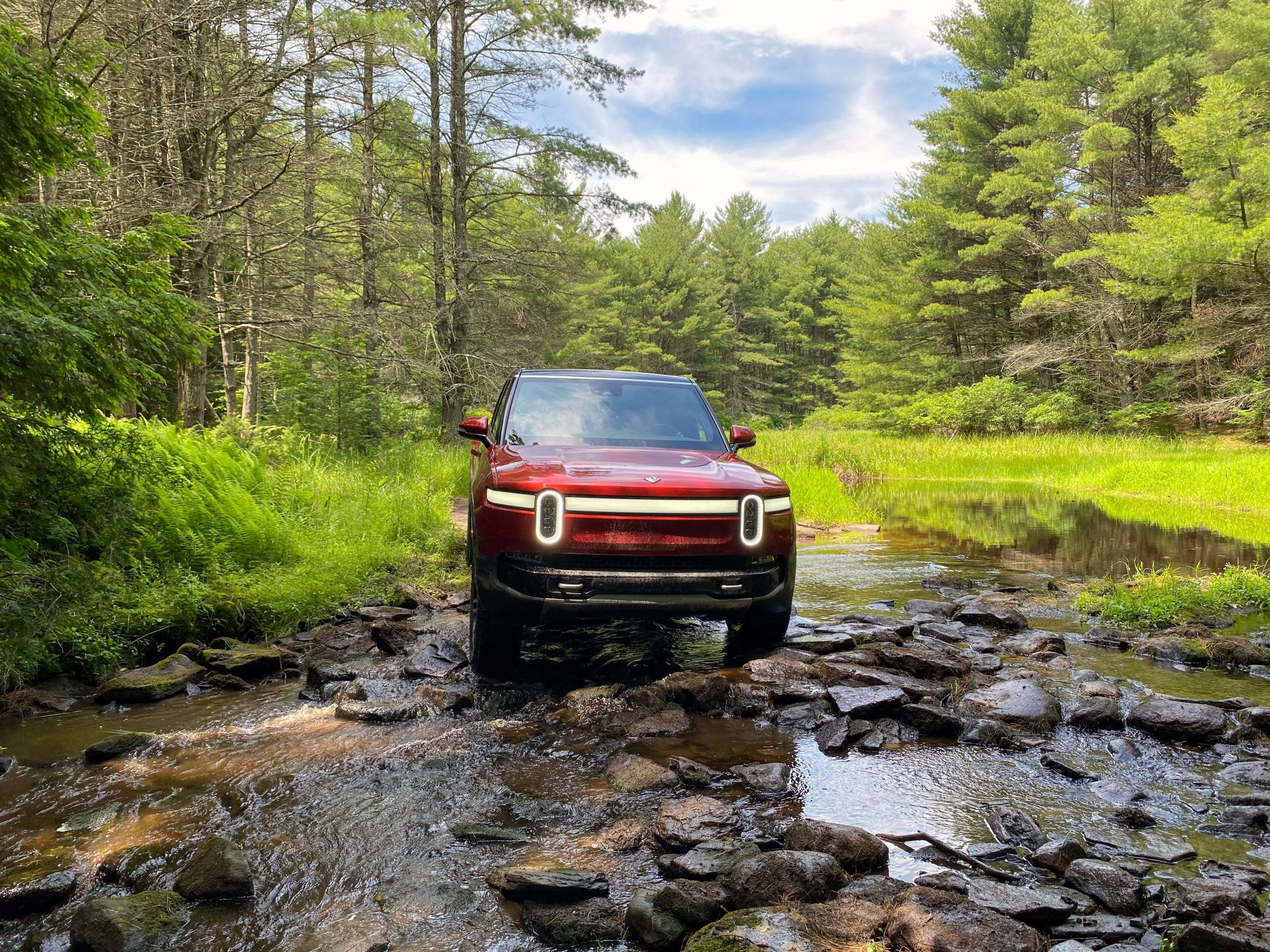 rivian r1s driving through a creek bed