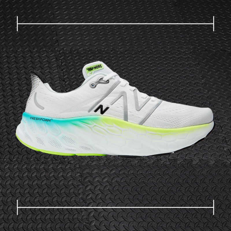 a white new balance fitness shoe with blue and green accents laid over top a photo of black rubber gym flooring