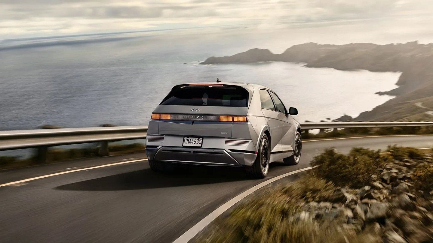 an electric hyundai driving down a road next to the ocean