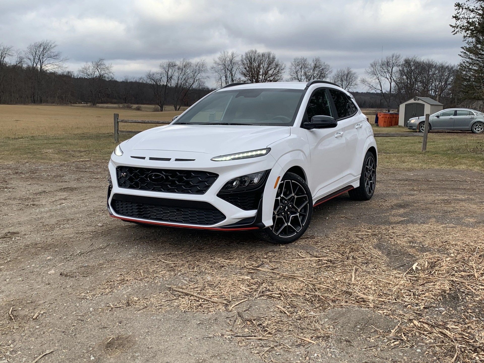 hyundai kona n parked in the dirt next to a field