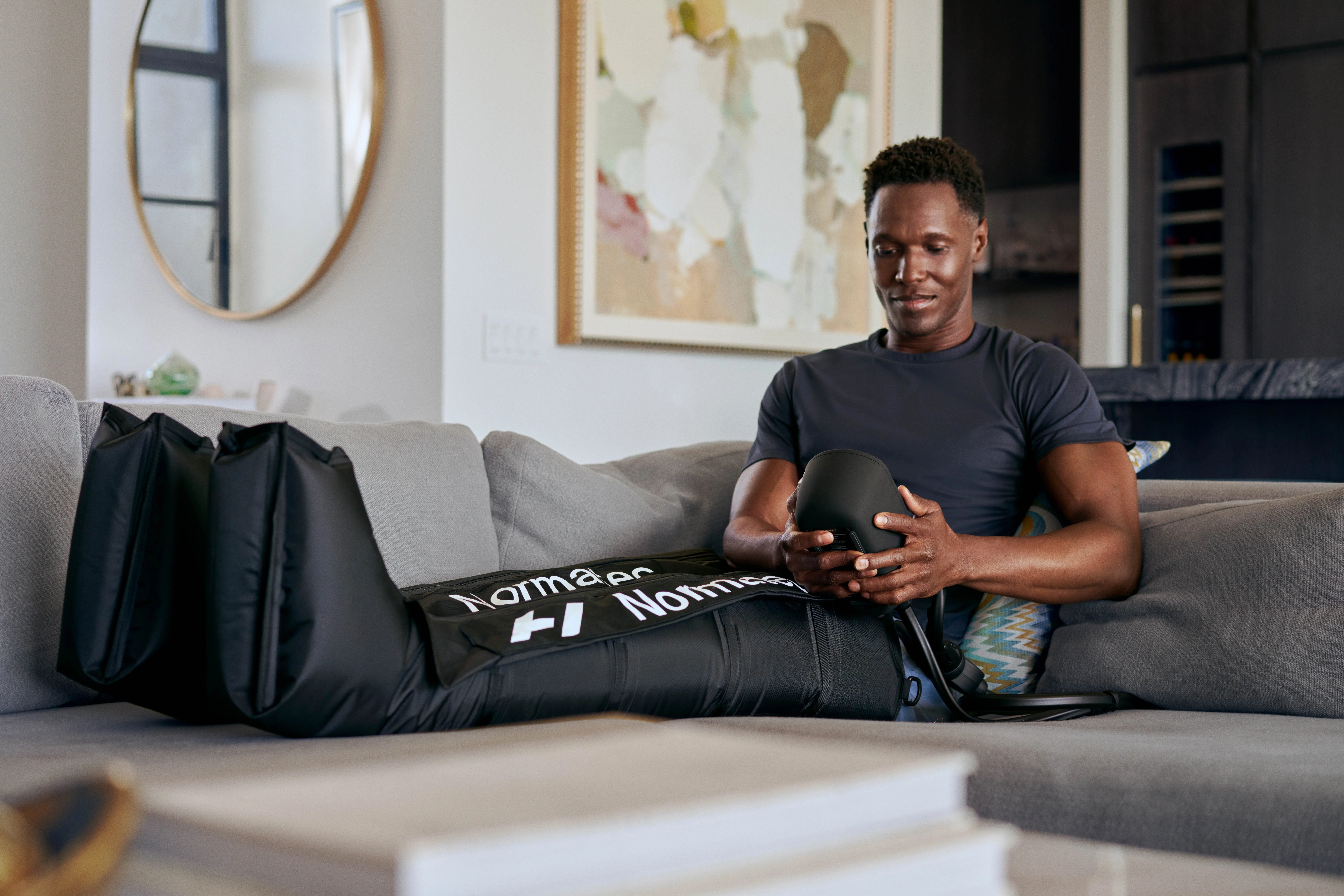 man sitting on couch using the normatec 3