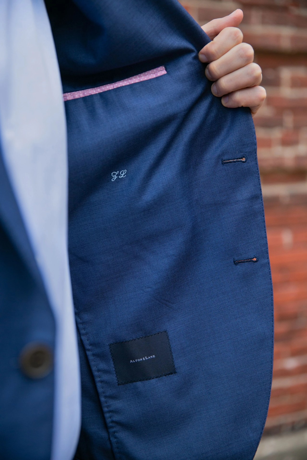 a man holding open a suit jacket to show the inner pocket and embroidered custom initials