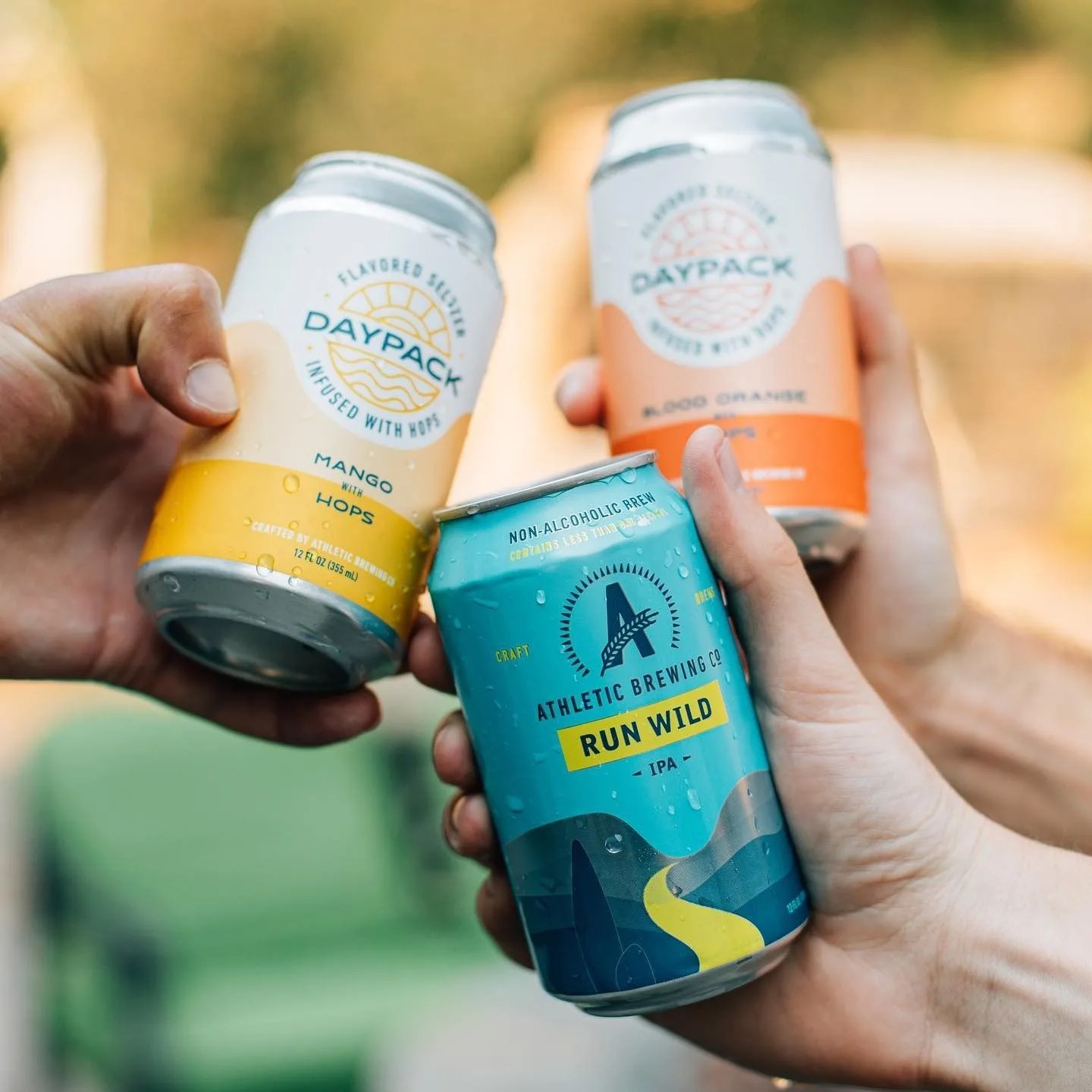 people cheersing with cans of athletic brewing