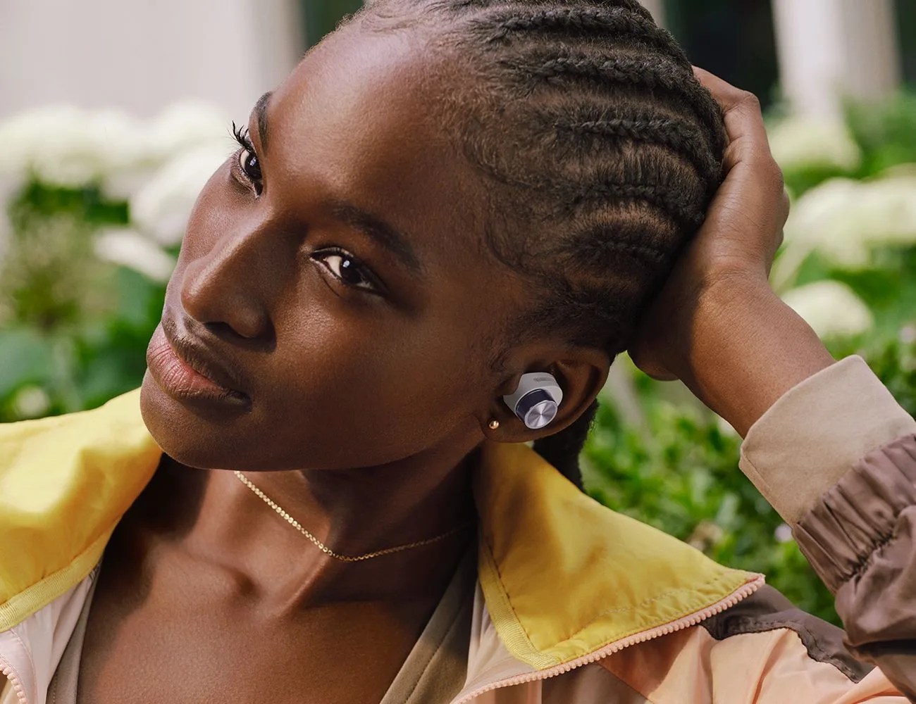 a woman looking to her right with a white and silver earbud in her left ear