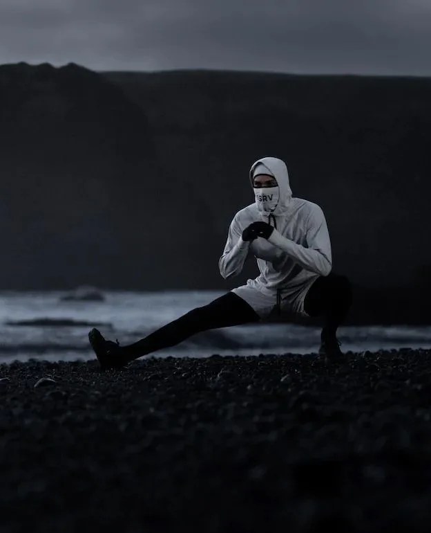 man stretching by beach wearing asrv waterproof winter 22 clothing