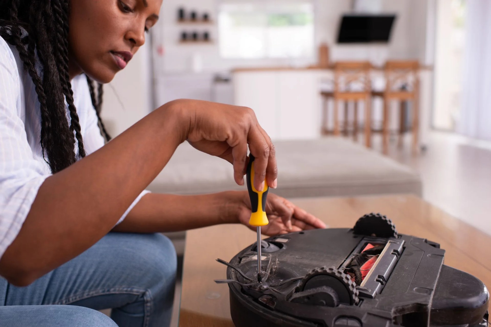modern housemaid making maintenance service to the robotic vacuum cleaner