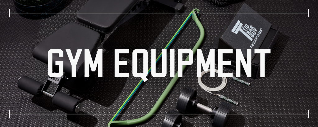 various pieces of gym equipment laid out on black rubber gym flooring with text saying gym equipment laid over top the photo