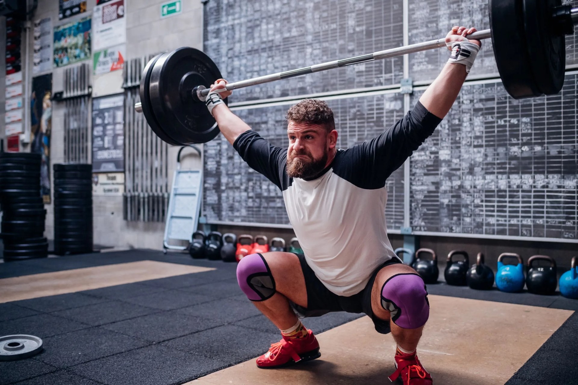 young man lifting barbell in gym