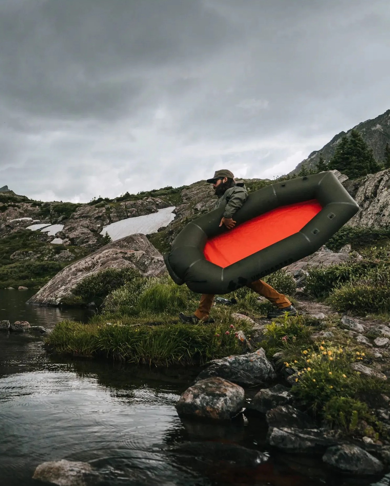 man carrying uncharted supply co's rapid raft to water
