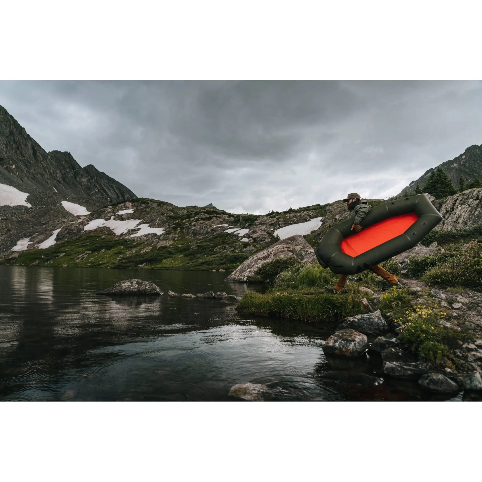 man carrying uncharted supply co's rapid raft to water