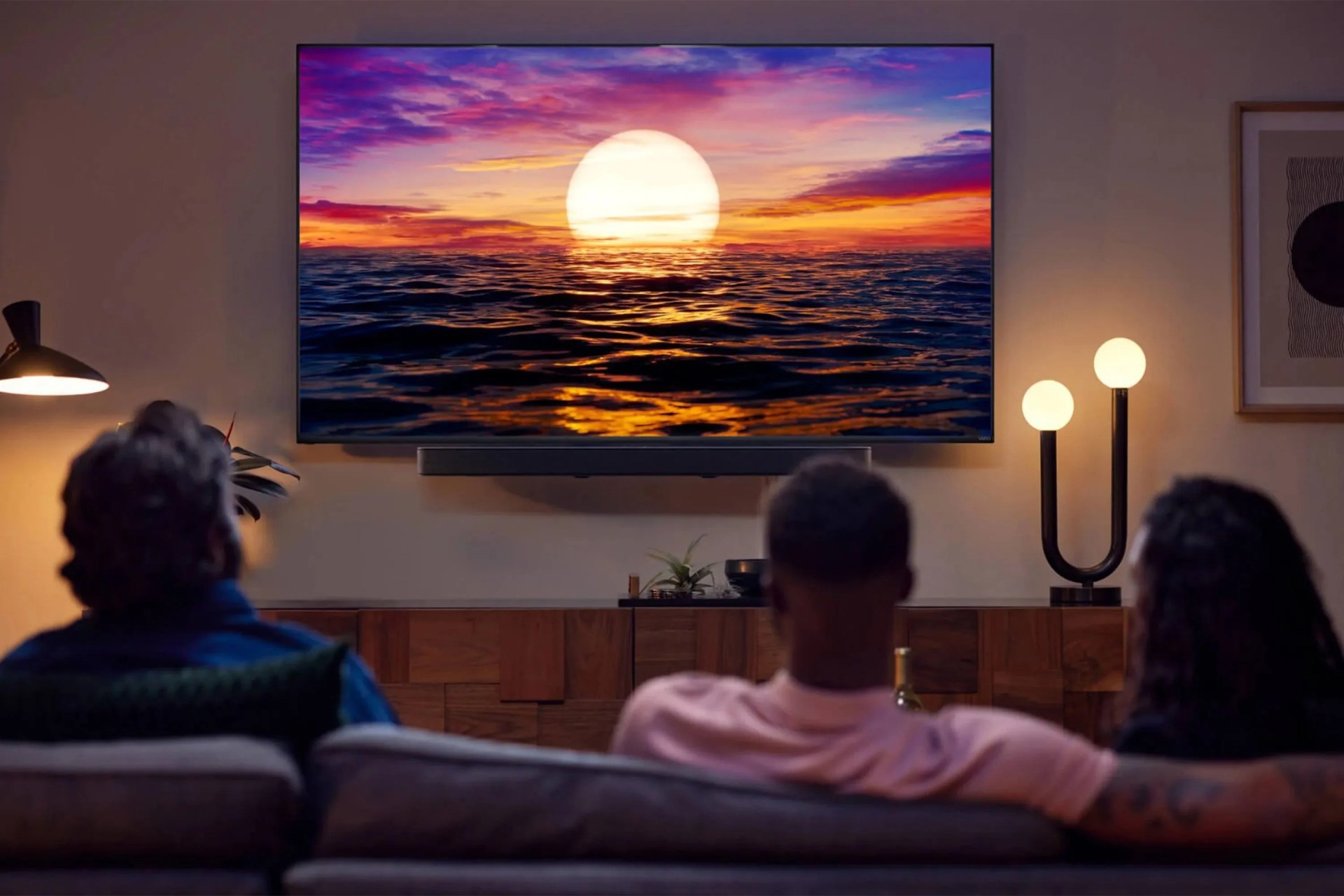 people sitting on a couch watch a sunset on a tv