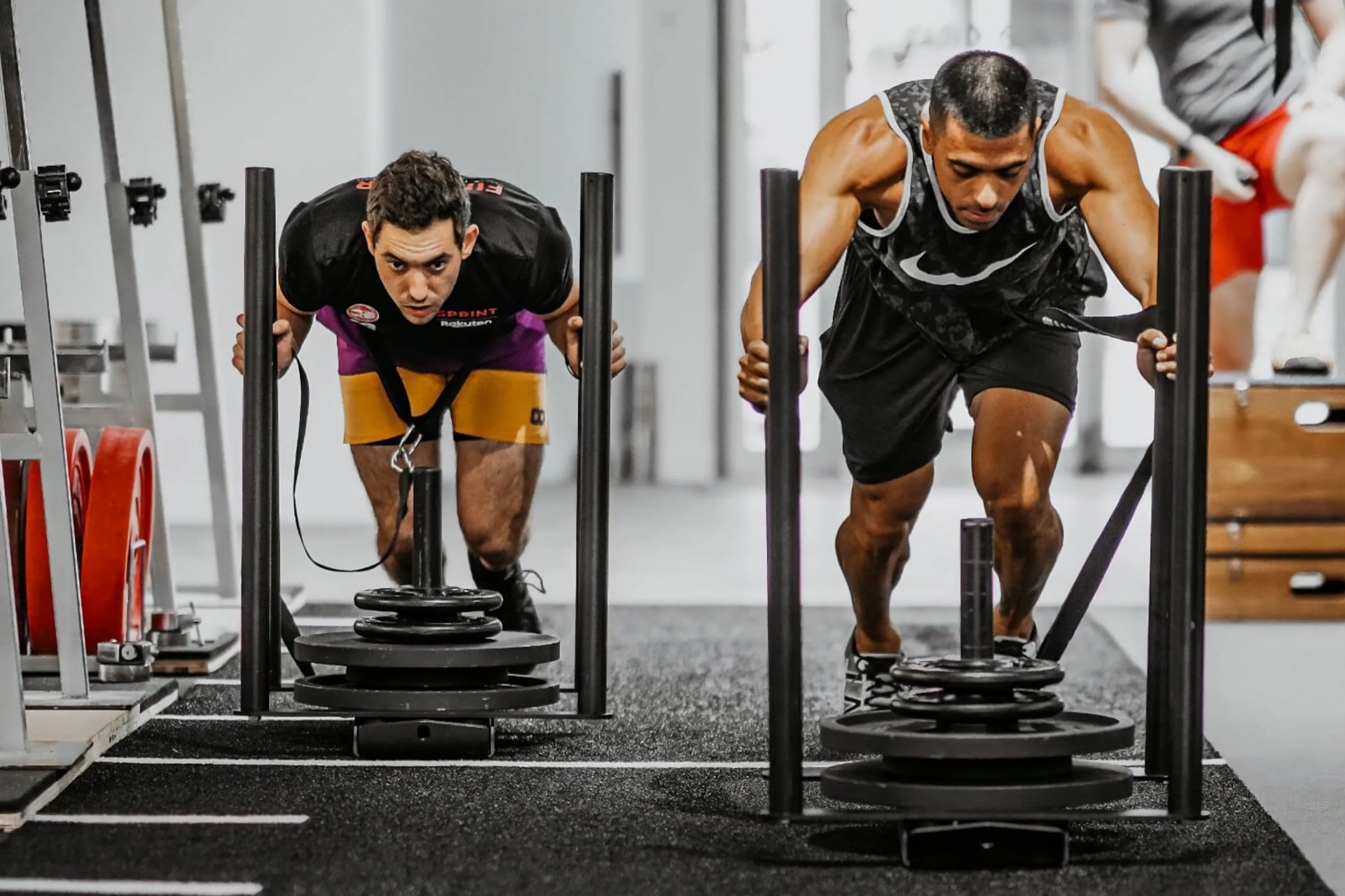 two men using workout sleds in a gym