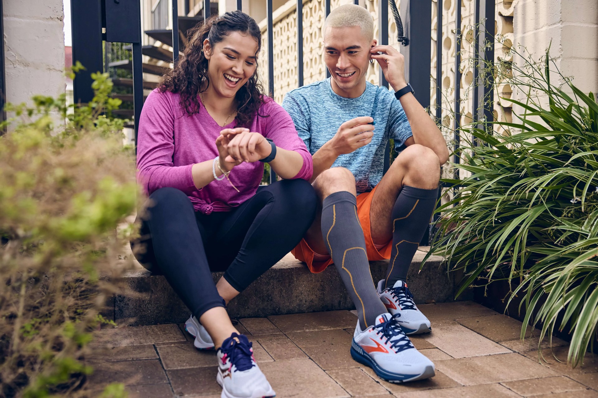 a man and woman sitting while looking at her watch wearing academy sports and outdoor sneakers