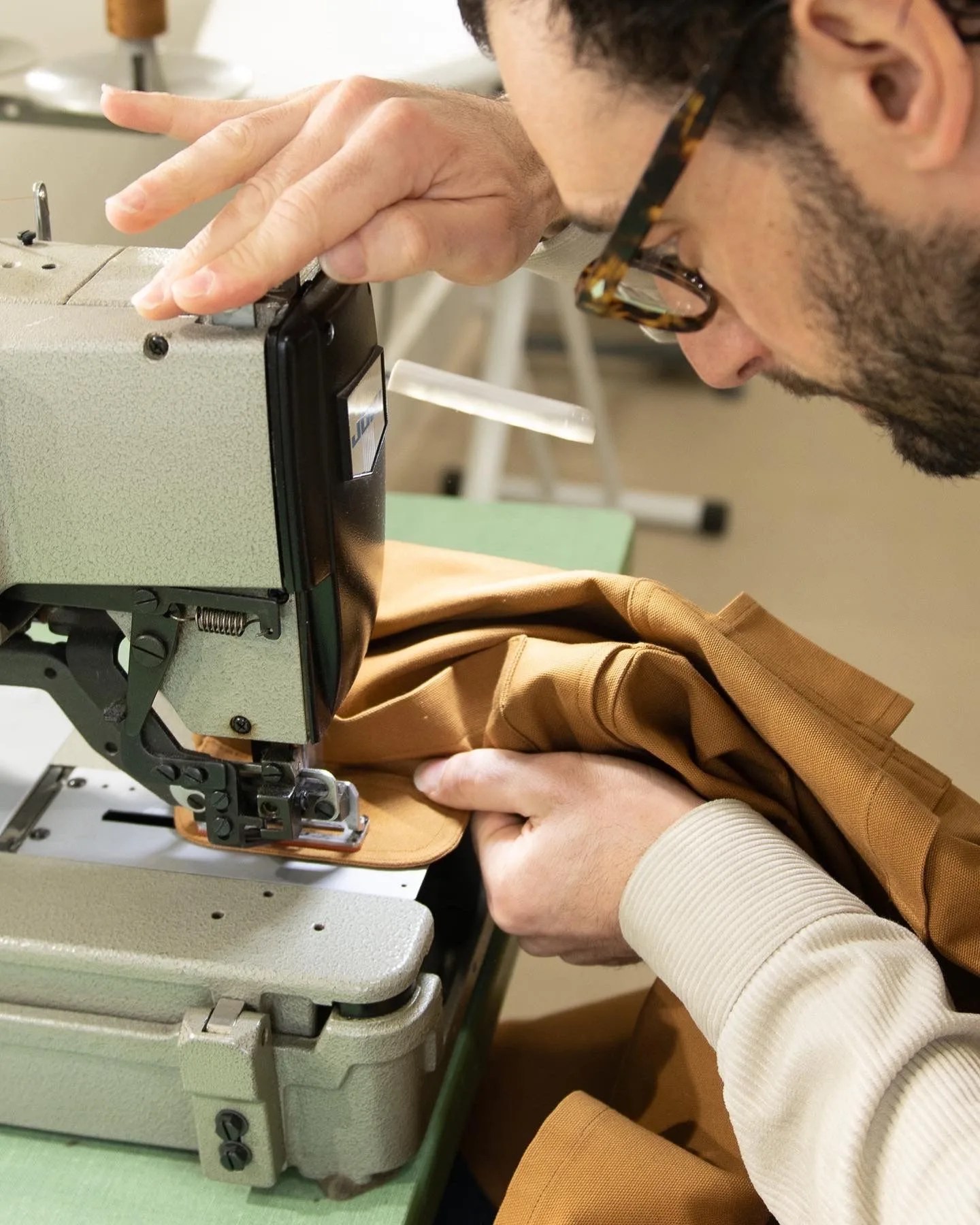 a man sewing a jacket on a sewing machine