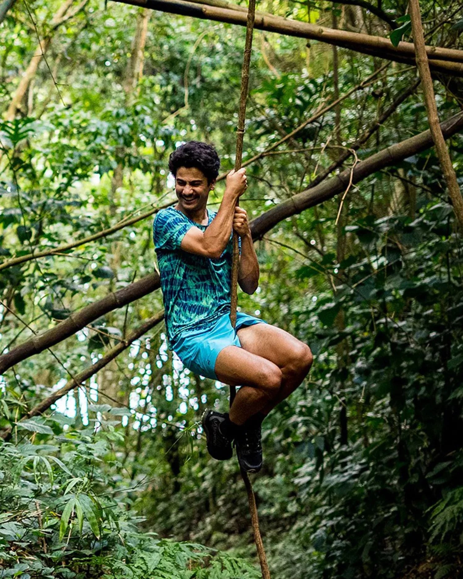 a man swinging from a vine in the forest