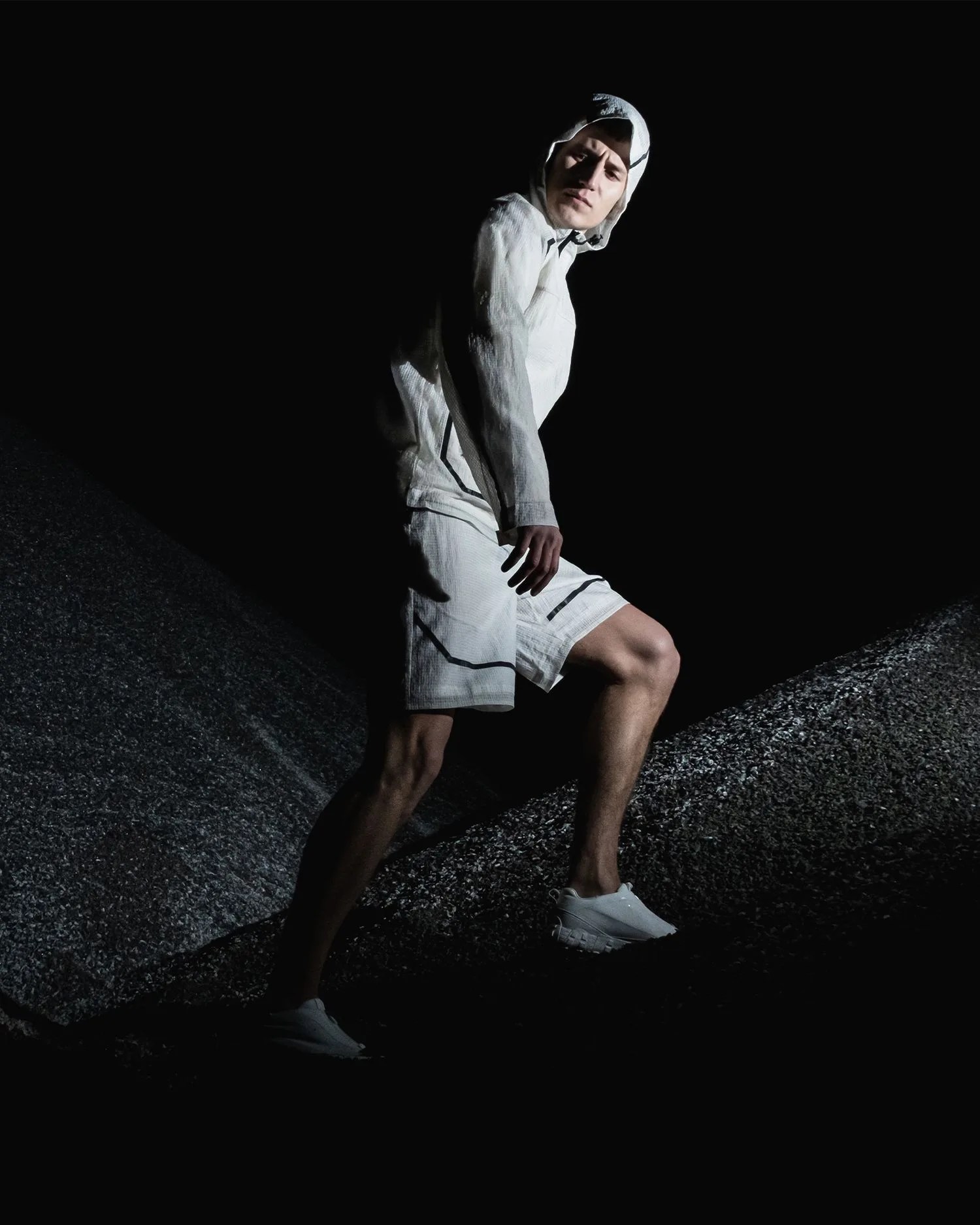a man wearing white walking up a mountain in the dark
