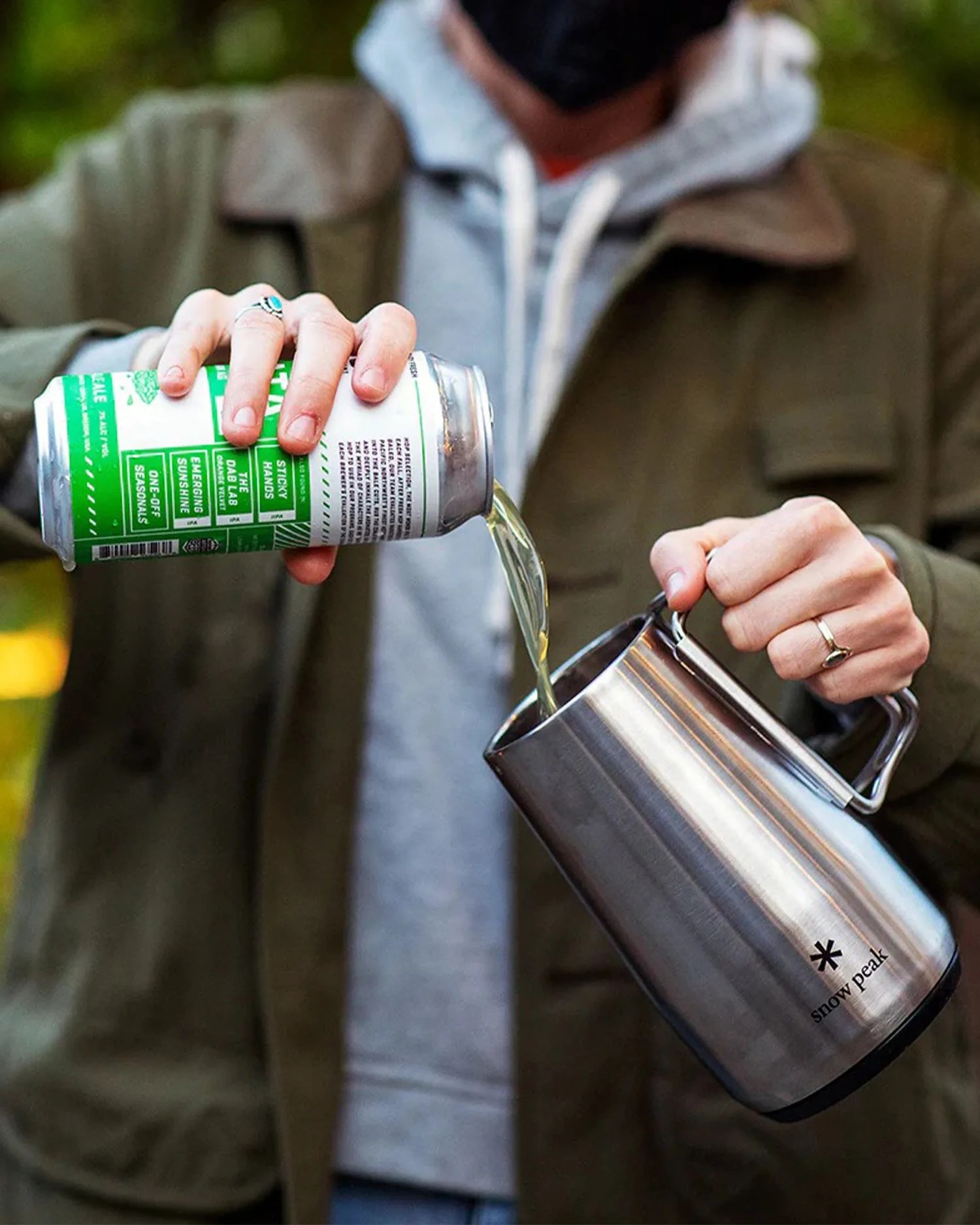 a person pouring a drink from a can into a metal stein