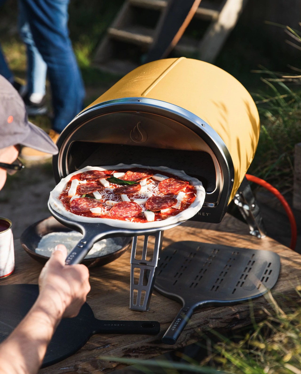 man putting pizza into gozney yellow pizza oven