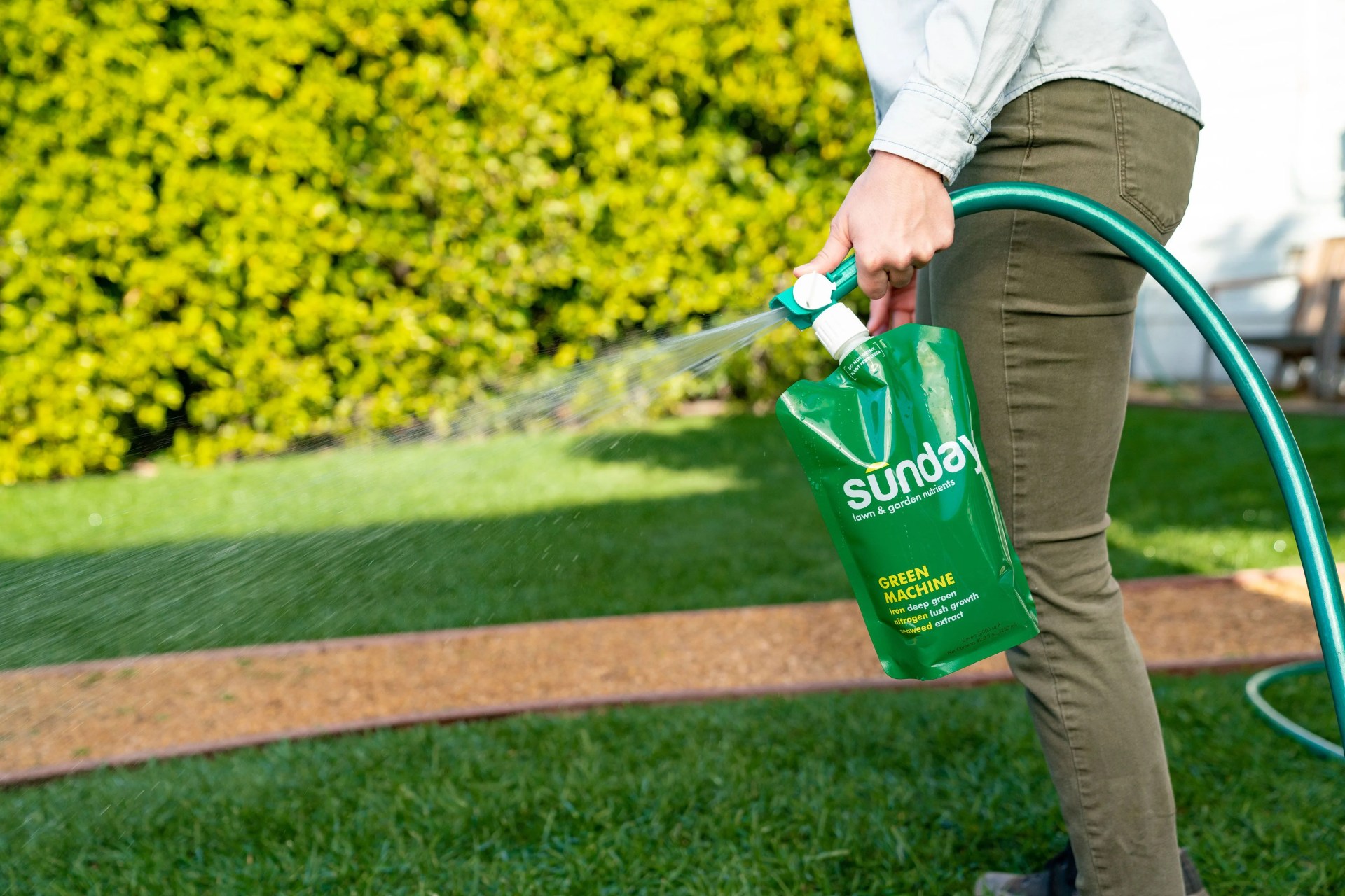 someone spraying sunday green machine on their lawn